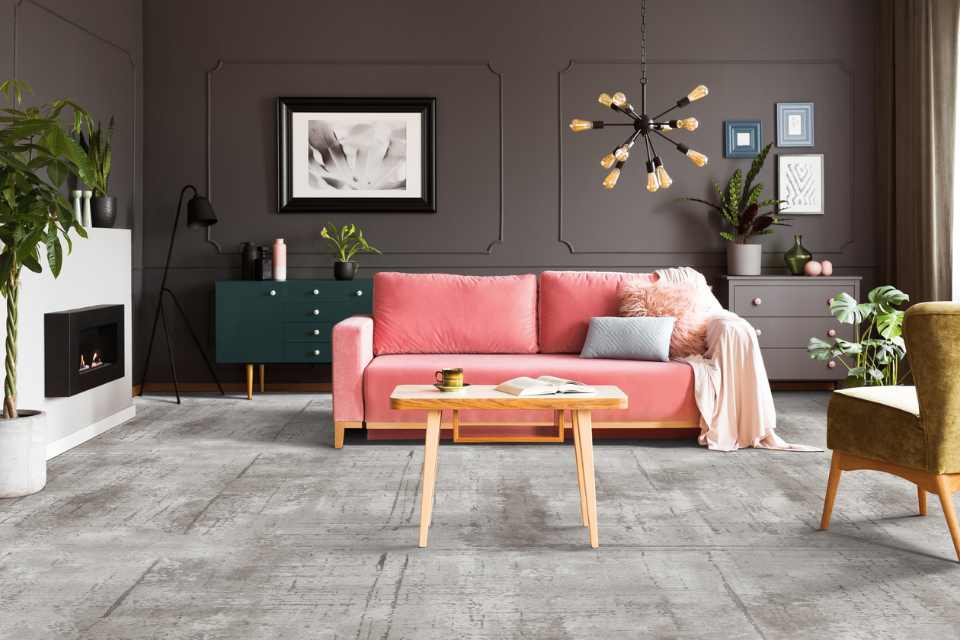 grey patterned carpet in jewel toned living room with pink velvet couch and accent lighting